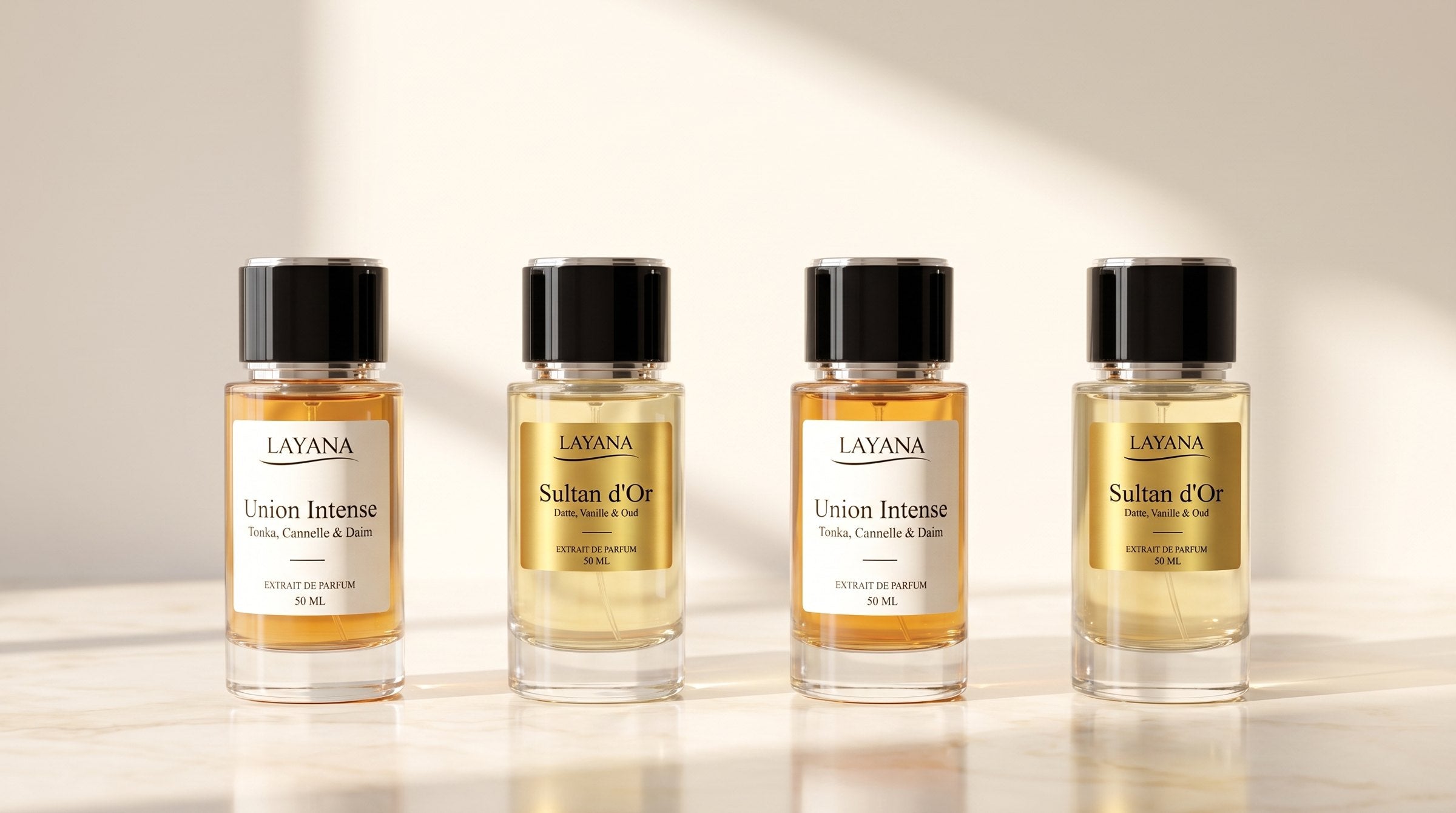 Rangée de flacons d’extrait de parfum Layana posés sur un marbre crème lumineux